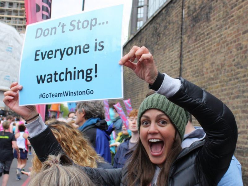 Female volunteer holding a sign saying Don't stop... everyone is watching